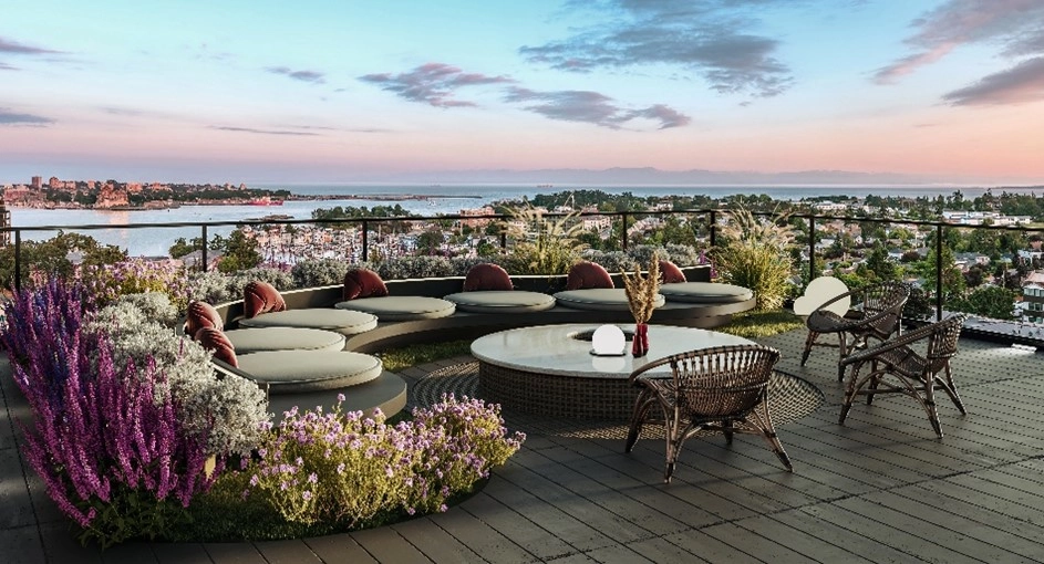 Apartment rooftop with curved sofas, pink, purple, and white flowers, round table, and two wooden chairs.