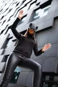 Low angle view of focused young female gesturing while wearing virtual reality glasses against modern building. providing instant emotional feedback on design choices and Architectural Visualization.